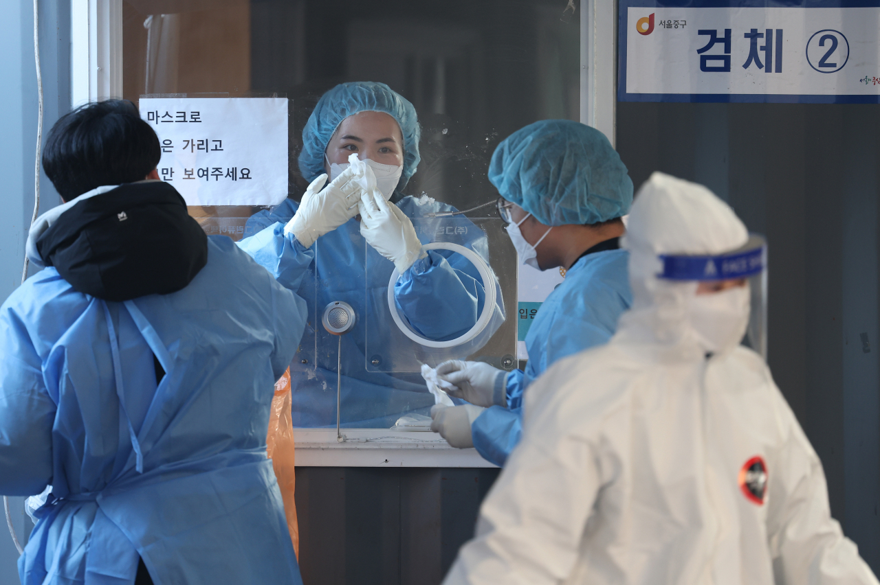 6일 오전 서울역 코로나19 임시 선별검사소에서 의료진이 유리벽에 붙은 얼음 조각을 긁어내고 있다. 이날 서울의 신규 확진자 수는 1208명으로 집계됐다. [연합]