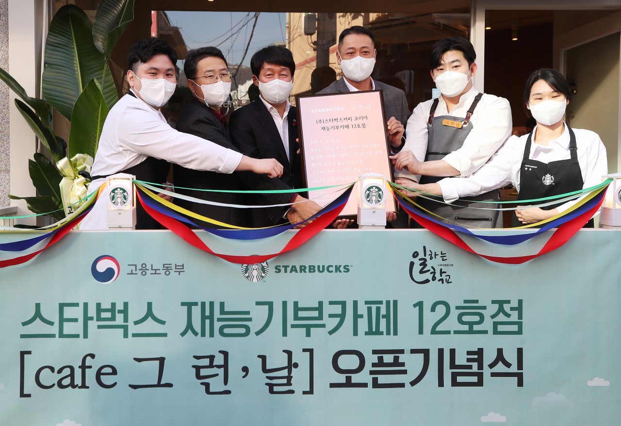지난해 12월 22일 오후 경기도 성남시의 한 카페에서 열린 스타벅스 재능기부카페 12호점 오픈 기념식에서 안경덕 고용노동부 장관, 송호섭 스타벅스커피코리아 대표, 이인환 일하는학교 이사장 등 참석자들이 현판을 들고 기념촬영을 하고 있다. [연합]