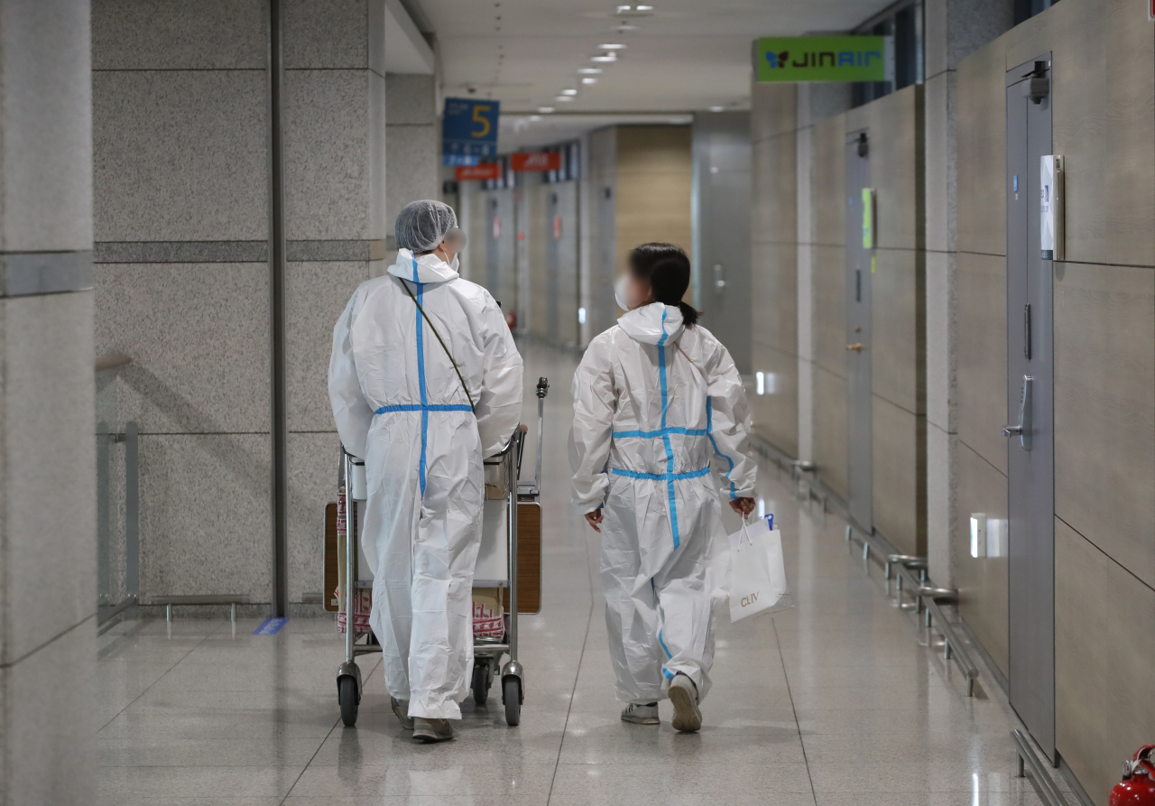 코로나19 변이 '오미크론' 확산이 우려되는 가운데 영종도 인천국제공항 제1여객터미널에서 방역복을 입은 항공사 관계자들이 이동하고 있다. [연합]