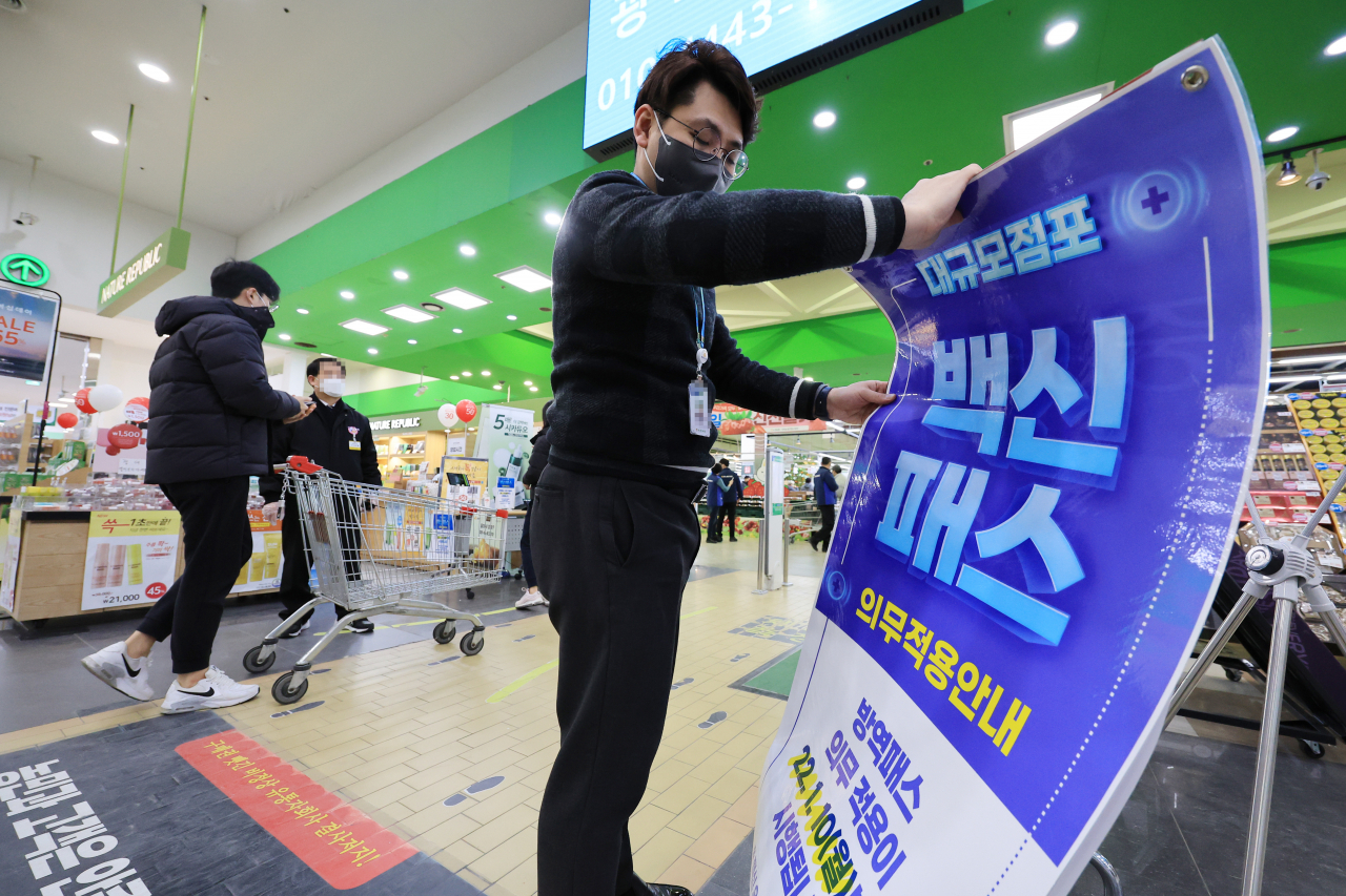 법원이 서울 마트·백화점에 대해 방역패스 효력 정지를 결정한 지난 14일 오후 서울 서초구 양재동 농협하나로마트에서 관계자가 방역패스 안내문을 치우던 모습. 연합뉴스