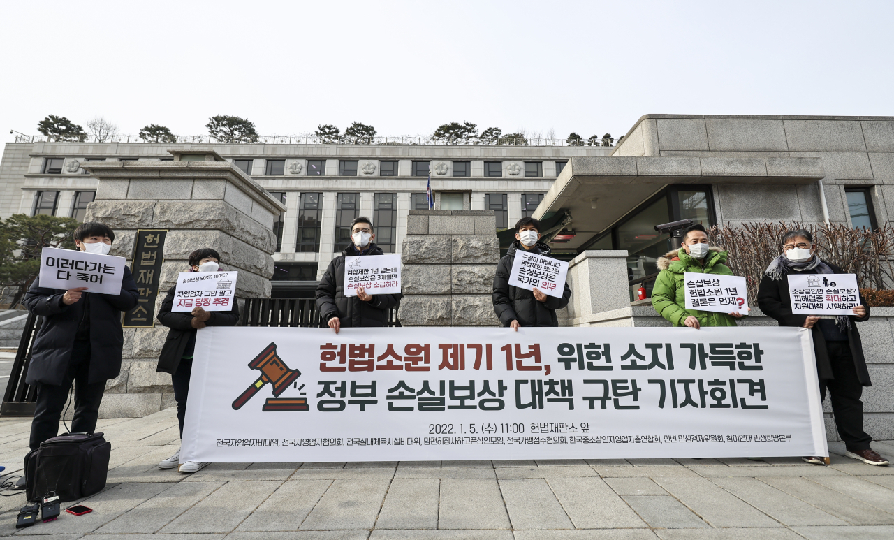 5일 헌법재판소 앞에서 열린 ‘헌법소원 제기 1년, 위헌 소지 가득한 정부 손실보상 대책 규탄 기자회견’에서 전국자영업자비대위 등 참석자들이 관련 내용이 적힌 손 피켓을 들고 서 있다. [연합]