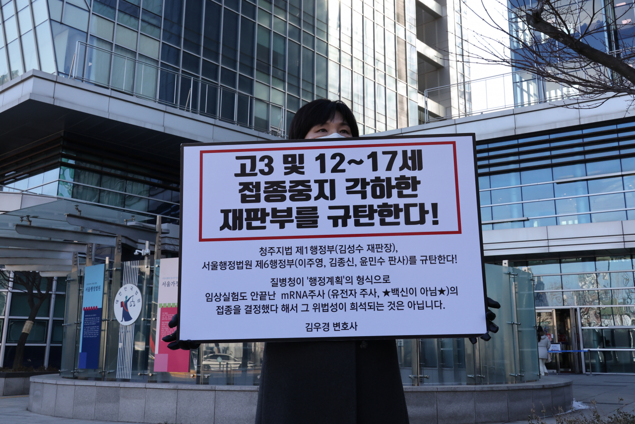 지난 14일 오후 서울 서초구 서울행정법원 앞에서 한 학부모가 고3 및 12~17세의 코로나19 백신 접종 중지를 각하한 재판부를 규탄하는 피켓시위를 하고 있다. [연합]