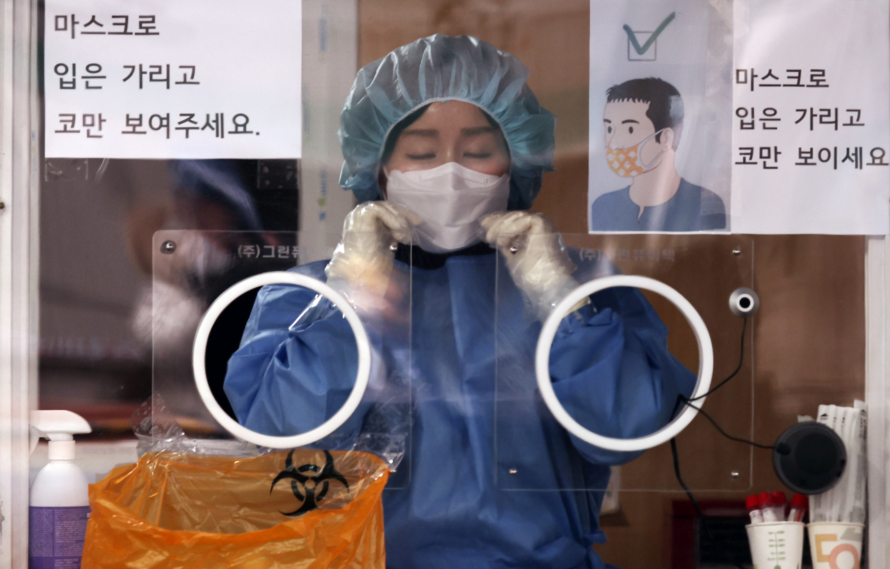 19일 서울 중구 서울역 광장 코로나19 임시 선별검사소에서 의료진이 검사 시작에 앞서 마스크를 고쳐 쓰고 있다. [연합]