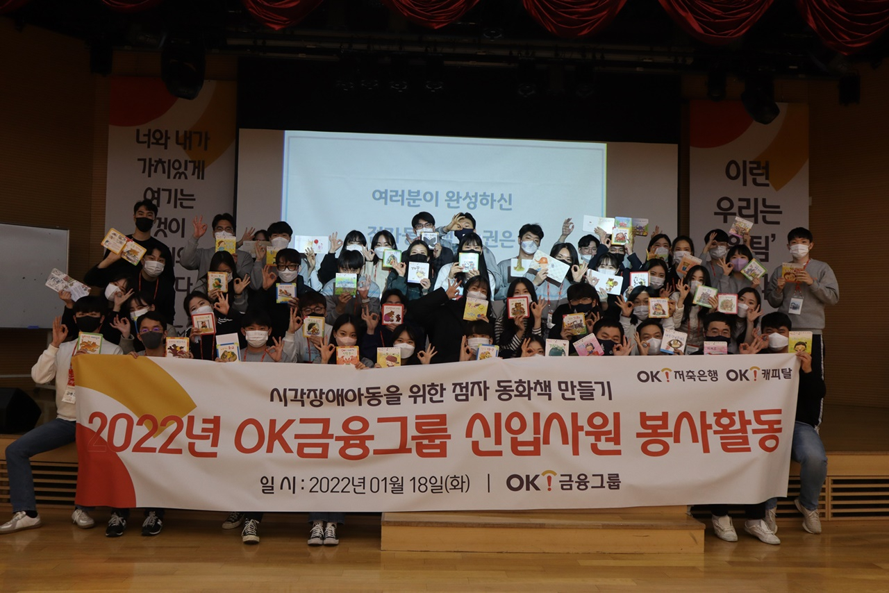 OK금융그룹은 지난 18일 자사 신입사원을 대상으로 ‘점자 동화책 만들기’ 봉사활동을 펼쳤다. 완성된 점자 동화책을 들고 포즈를 취한 신입사원들이 기념촬영을 하고 있다. [OK금융그룹 제공]