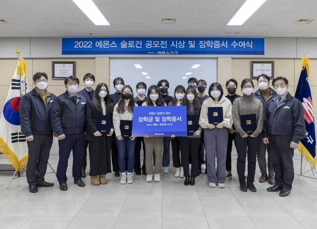 김경수 에몬스가구 회장(오른쪽)이 지난 19일 인천 고잔동 본사에서 장학금 수여식을 마치고 12명의 대학생들과 기념사진을 촬영했다.[에몬스가구 제공]