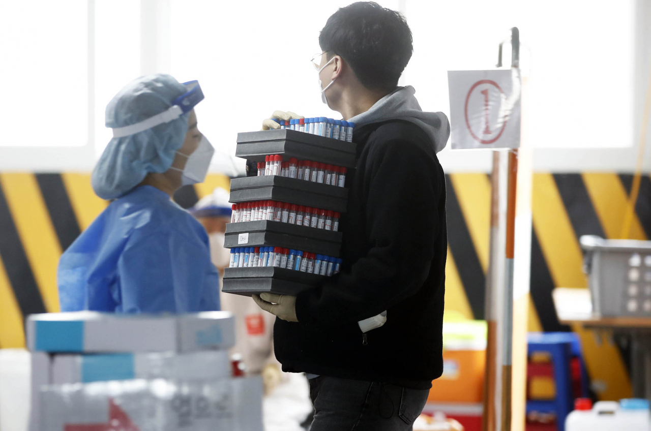 24일 오전 광주 북구 선별진료소에서 보건소 직원이 코로나19 검사를 의뢰할 검체를 옮기고 있다. 연합뉴스