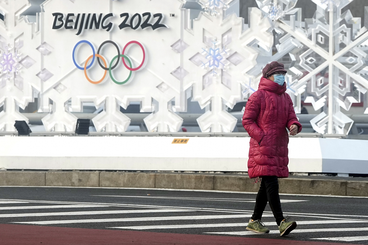 한 중국 시민이 25일 2022년 베이징동계올림픽이 열리는 올림픽 공원 앞을 지나고 있다. [AP]