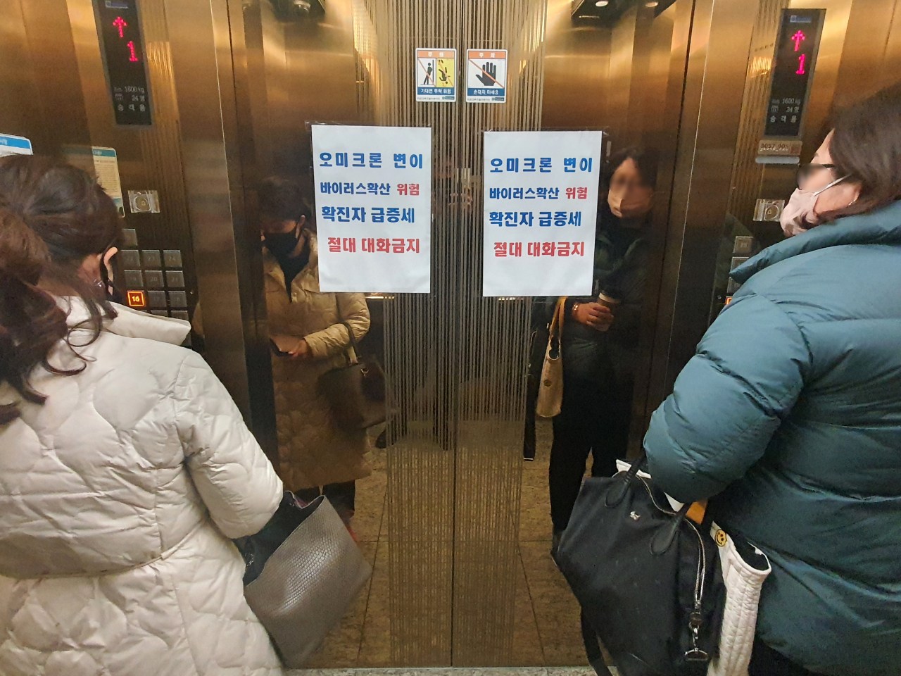 지난 25일 오후 부산 해운대구 재송동 한국승강기안전공단 부산동부지사 승강기에 ‘오미크론 변이 확산으로 확진자가 급증하고 있으니 대화 금지’라는 안내문이 붙어 있다. [연합]