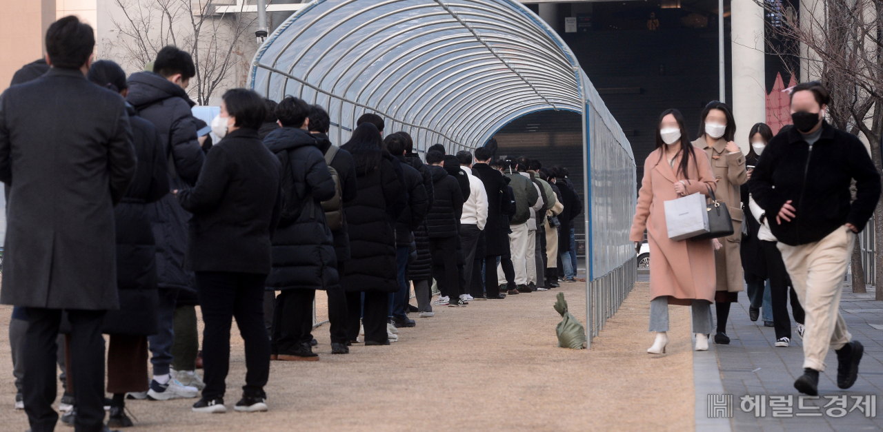 국내 코로나19 신규 확진자수가 역대 하루 최다인 1만3012명을 기록한 26일 오전 서울 용산역 앞에 마련된 임시선별검사소에 검사를 받기 위해 대기하는 시민들과 인근으로 출근하는 시민들의 모습이 대조를 이루고 있다. [박해묵 기자]