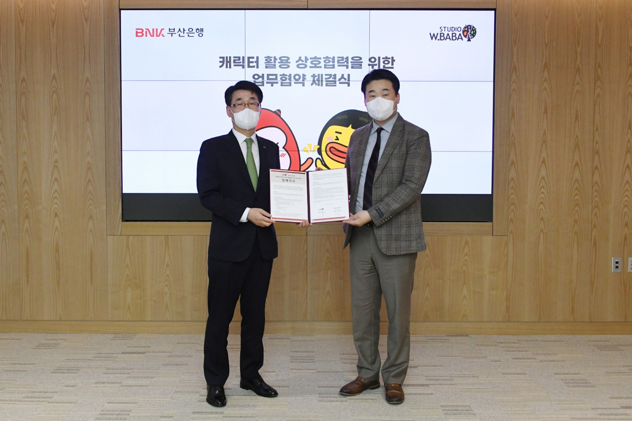 BNK부산은행은 25일 오후, 부산은행 본점에서 애니메이션 제작 전문기업인 ‘스튜디오더블유바바’와 캐릭터 콘텐츠 활용을 위한 업무 협약식을 체결했다고 밝혔다.(사진 왼쪽부터 부산은행 강상길 디지털금융본부장, 스튜디오더블유바바㈜ 이홍주 대표) [부산은행 제공]