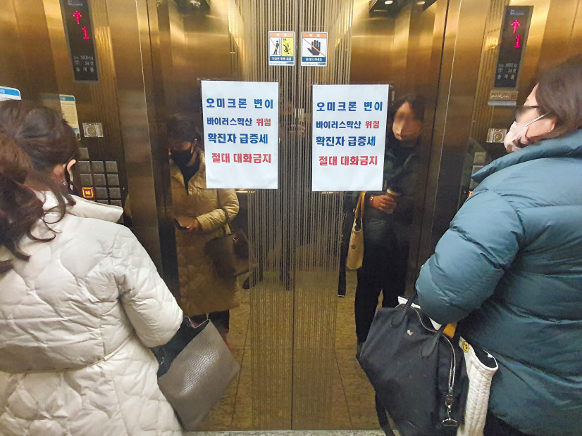 지난 25일 오후 부산 해운대구 재송동 한국승강기안전공단 부산동부지사 승강기에 ‘오미크론 변이 확산으로 확진자가 급증하고 있으니 대화 금지’라는 안내문이 붙어 있다. [연합]