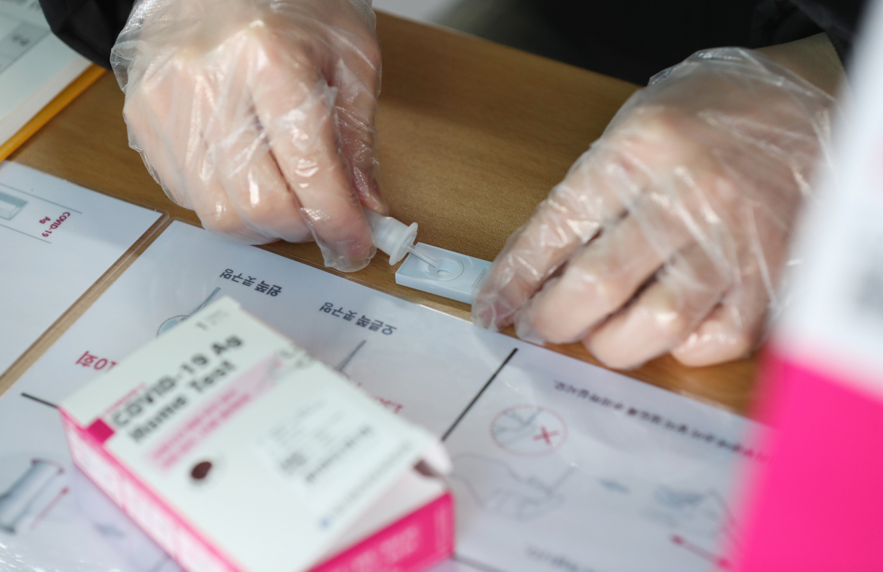 오미크론 대응체계가 일부 지역에서 시행된 26일 오전 광주 북구 선별진료소에서 검사자가 '자가 진단 키트' 로 신속 항원 검사를 스스로 하고 있다. 오미크론 변이가 일찌감치 우세종이 된 광주, 전남 평택, 안성 등 4개 지역은 이날부터 선별진료소에 신속항원검사를 도입하고, 고위험군에 대해서만 기존 유전자 증폭 검사(PCR)를 한다. [연합]