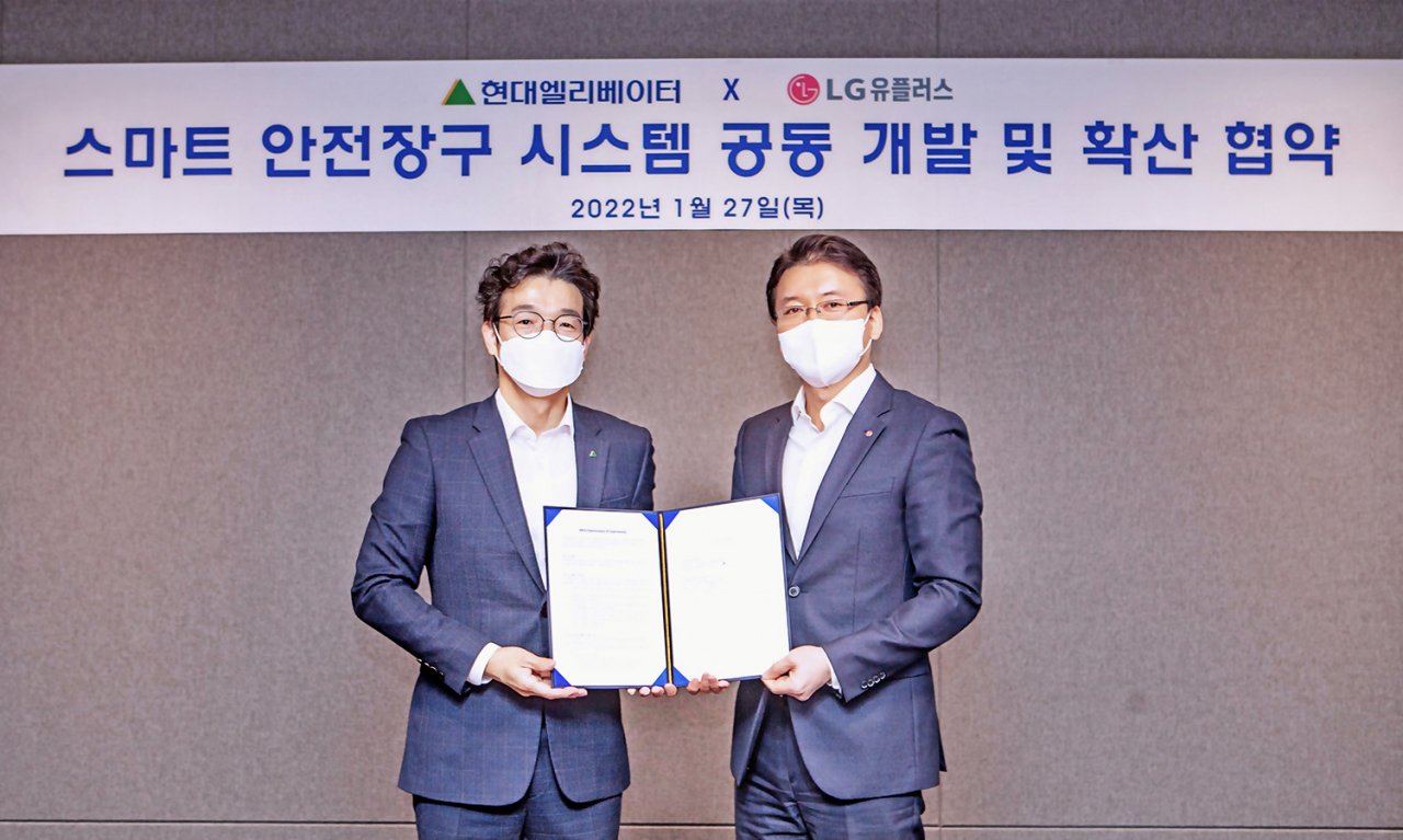 LGU+와 현대엘리베이터는 ‘스마트 안전장구 시스템 공동 개발 및 확산 협력’에 관한 업무협약(MOU)을 27일 체결했다. 사진은 전승훈LGU+ 스마트인프라사업담당과 이정한 현대엘리베이터 최고안전환경책임자(왼쪽) 기념 촬영하고 있는 모습. [LGU+ 제공]