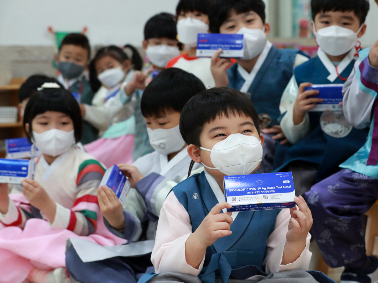 27일 오전 부산 남구 무지개유치원에서 한복을 입은 원생들이 선생님으로부터 신속항원검사키트(자가진단키트)를 지급받은 뒤 설명을 듣고 있다. 아동들은 이날 설을 앞두고 예절교육과 함께 진단키트 사용 방법과 필요성 등을 교육받았다. 부산 남구는 관내 모든 어린이집 에 5천500명분, 유치원에 3천250명분에 설을 앞두고 자가 진단키트를 긴급지원 했다. 이번 지원은 최근 오미크론 변이 확산과 설 연휴 대규모 이동으로 인해 백신 접종의 사각지대에 있는 아동 건강을 위해 준비됐다.[연합]