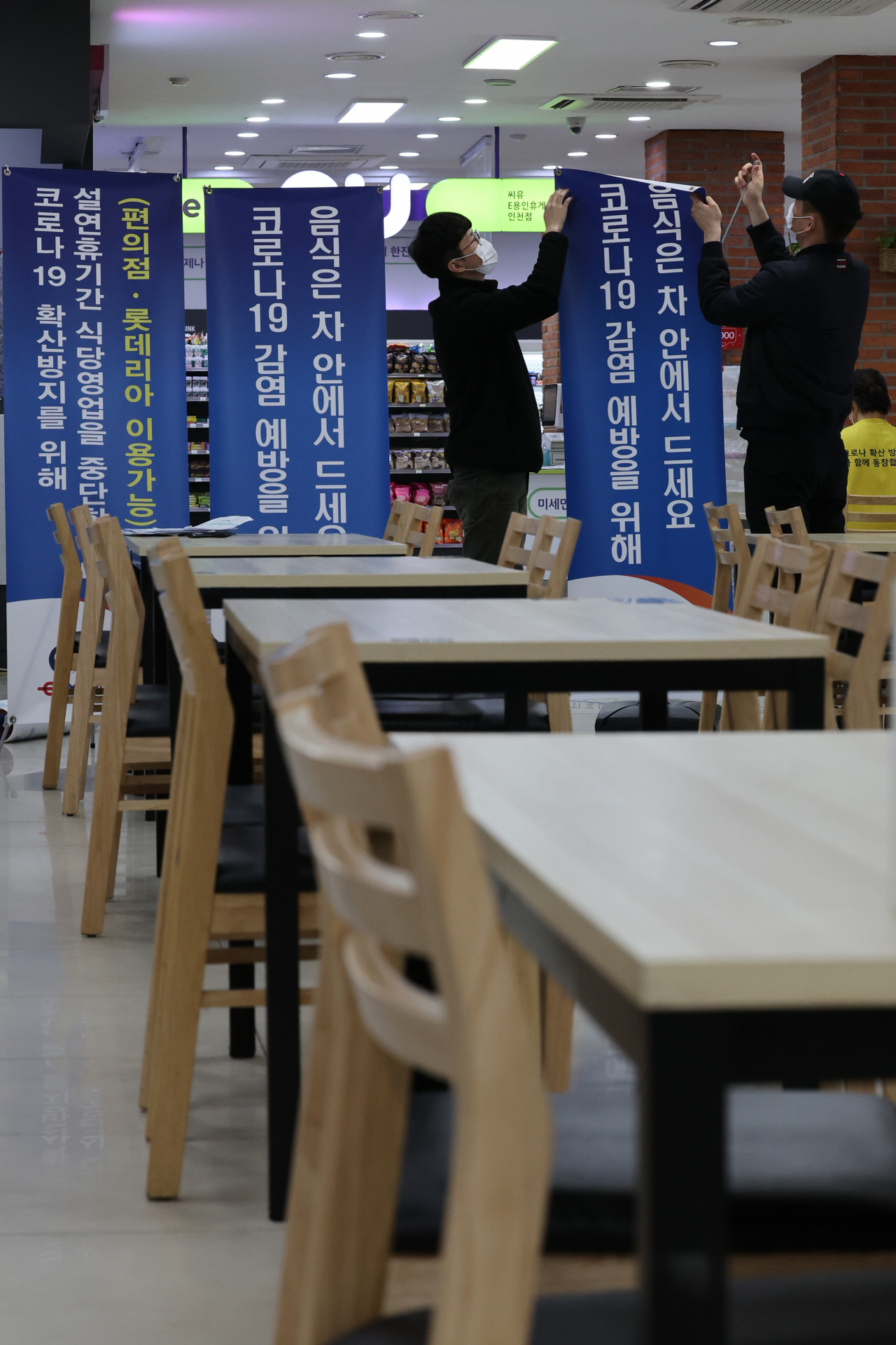 설 연휴를 하루 앞둔 28일 오후 용인시 처인구 용인휴게소(인천 방향)에서 직원들이 코로나19 확산 방지를 위해 매장 내 식사를 금지하고 포장만 허용한다는 안내문을 붙이고 있다. 연합뉴스