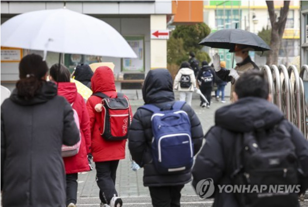 25일 오전 개학을 맞은 서울의 한 초등학교에서 학생들이 학교보안관과 인사를 나누며 등교하고 있다.[출처: 연합]