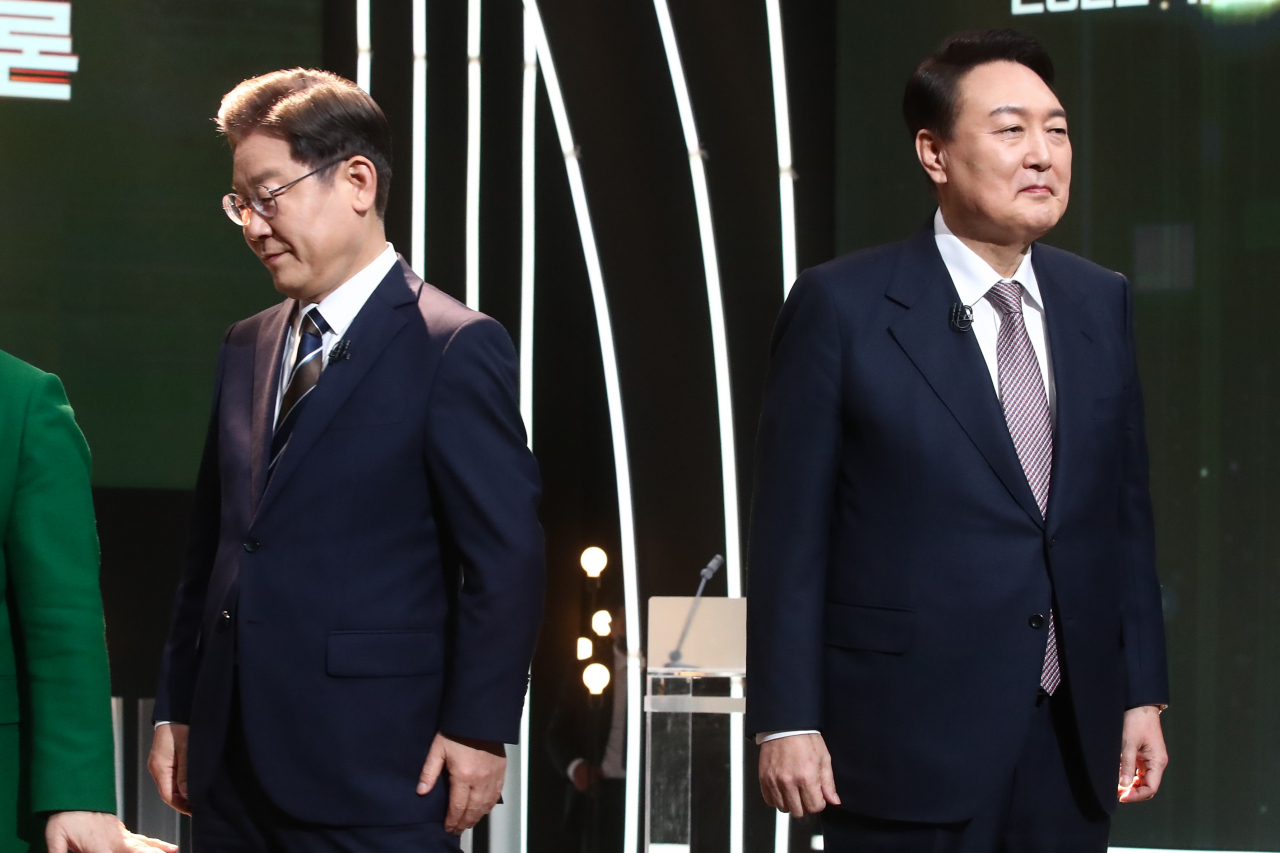 3일 오후 서울 여의도 KBS 공개홀에서 열린 방송 3사 합동 초청 '2022 대선후보 토론'에서 더불어민주당 이재명 대선 후보(왼쪽)가 기념촬영을 마친 뒤 자리로 돌아가고 있다. 오른쪽은 국민의힘 윤석열 대선 후보. [연합]