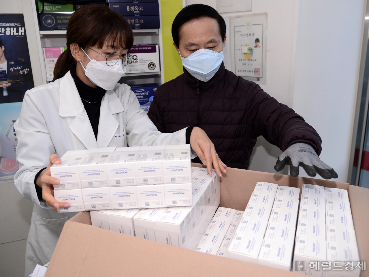 서울 금천구의 한 약국에서 약사와 유통업체 관계자가 먹는 코로나19 치료제인 '팍스로이드'를 살펴보고 있다. [박해묵 기자]