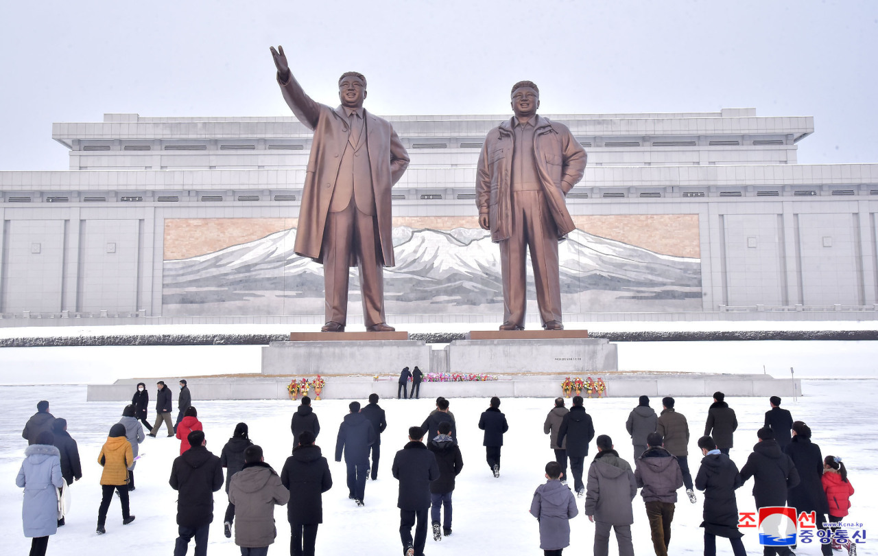 North Korean people lay flowers and pay respect to the statues of the late North Korean leaders, Kim Il-sung and Kim Jong-Il on Feb. 2. (Yonhap)