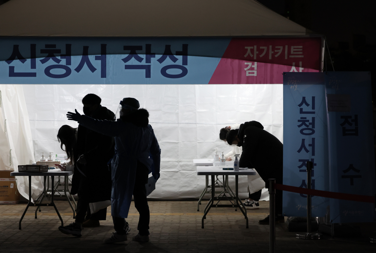 8일 오후 서울 마포구 월드컵공원 평화광장에 마련된 코로나19 임시 선별검사소에서 시민들이 신속항원검사를 받기 위해 신청서를 작성하고 있다. [연합]