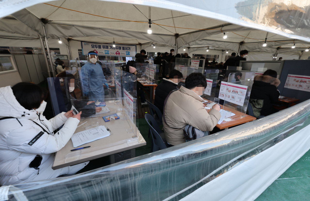Citizens receive rapid antigen tests at a test center in eastern Seoul on Wednesday. (Yonhap)
