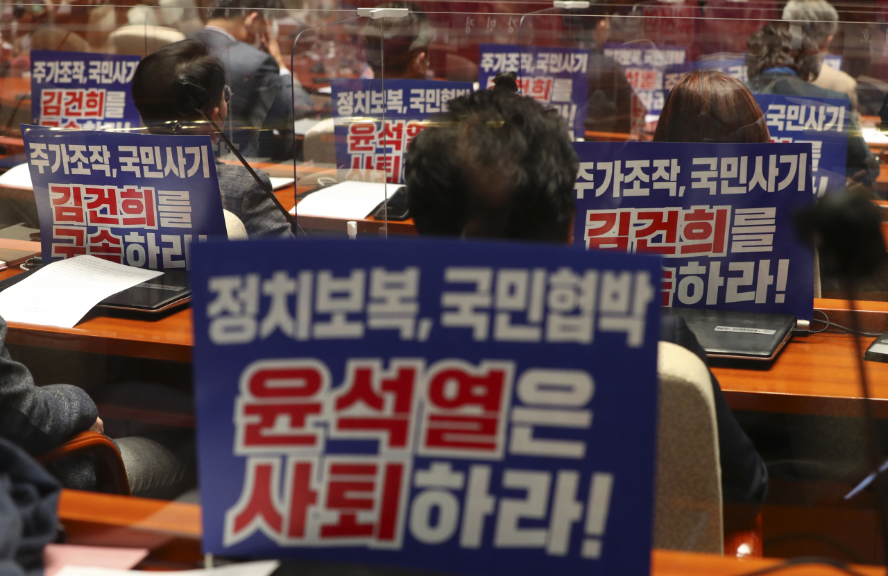 10일 서울 여의도 국회에서 열린 의원총회에 참석한 더불어민주당 의원들의 자리에 '윤석열 대선 후보 사퇴 촉구와 부인 김건희 구속 촉구' 메시지가 적힌 피켓이 붙어 있다. [연합]