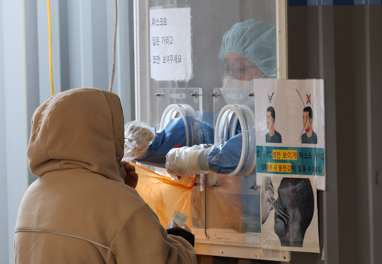 This Jan. 23, 2022, file photo shows a medical worker conducting a COVID-19 test on a person at a temporary virus testing center in central Seoul. (Yonhap)