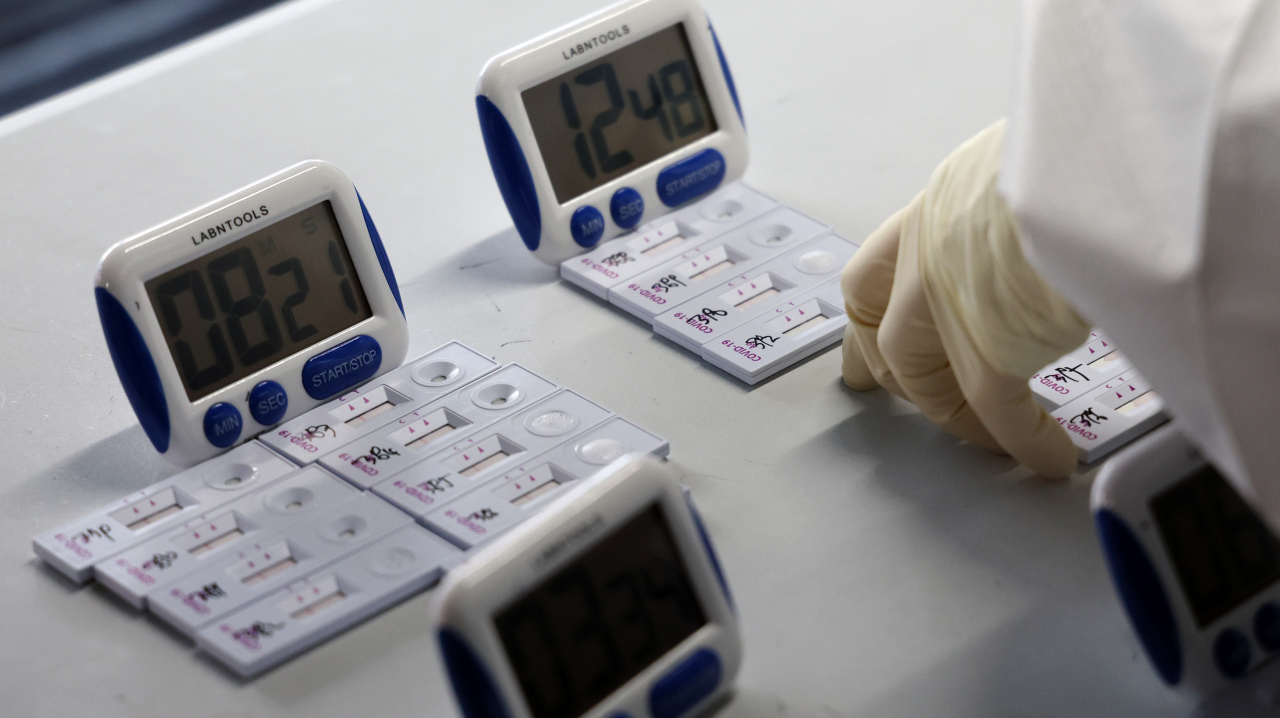 A health worker checks rapid antigen test kits at a makeshift COVID-19 testing clinic in Seoul last Thursday. (Yonhap)