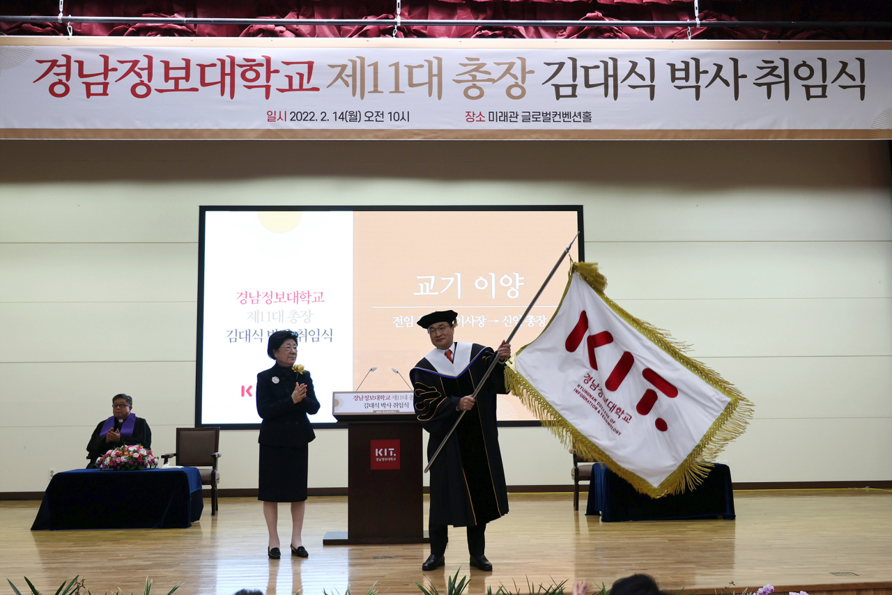 경남정보대학교 제 11대 총장에 취임한 김대식 박사가 교기를 이양받고 있다. [경남정보대 제공]