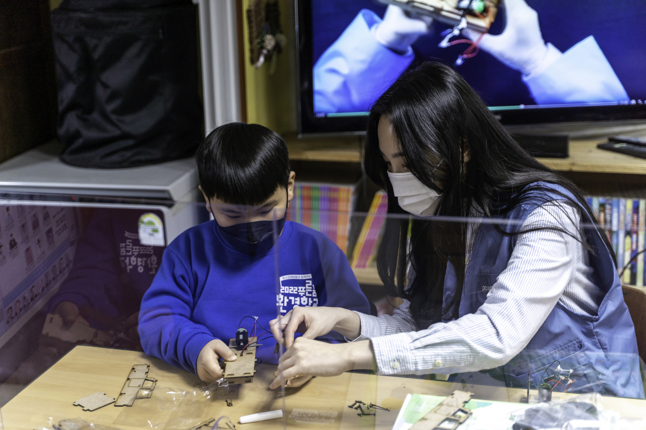 포스코케미칼 직원이 포항 지역아동센터에서 진행한 ‘푸른꿈 환경학교’에서 전기차 모형을 함께 조립하고 있다. [포스코케미칼 제공]