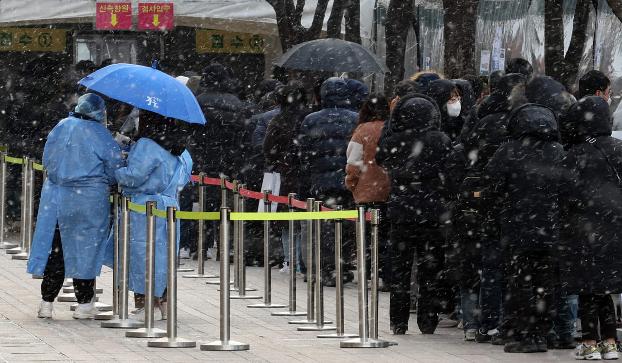 눈발과 추위가 찾아온 15일 서울 중구 서울광장 선별진료소에서 시민들이 검사를 기다리고 있다. 이날 0시 기준 신규 확진자는 5만7177명이다. [연합]