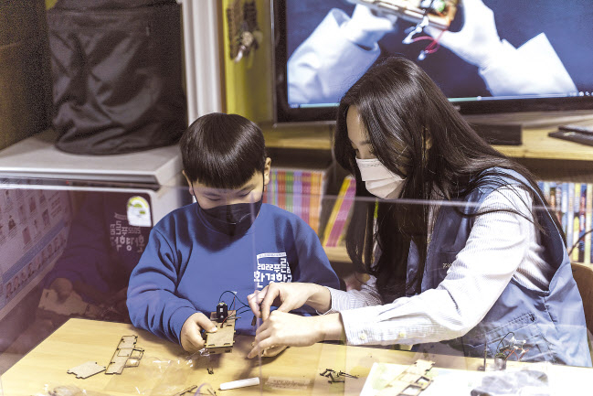 포스코케미칼 직원이 포항 지역아동센터에서 진행한 ‘푸른꿈 환경학교’에서 전기차 모형을 함께 조립하고 있다. [포스코케미칼 제공]