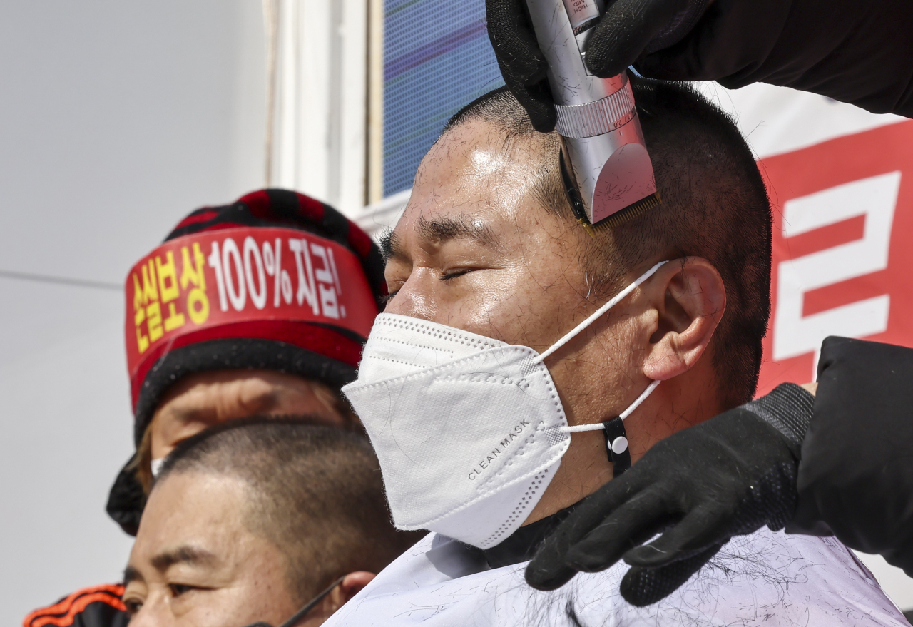 15일 오후 서울 광화문 열린마당에서 열린 ‘코로나 피해 실질 보상 촉구 및 정부 규탄대회’에서 자영업자들이 삭발식을 하고 있다. [연합]