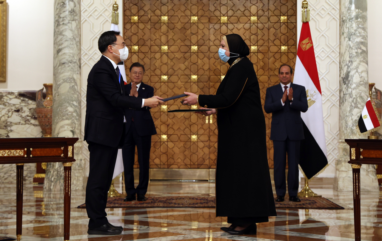 South Korean Trade, Industry and Energy Minister Moon Sung-wook (L) and his Egyptian counterpart Nevine Gamea (R) exchange the memorandum of understanding for joint research on trade and economic partnerships between the two countries as South Korean President Moon Jae-in (L, rear) and Egyptian President Abdel Fattah el-Sisi (R, rear) watch after their summit talks at the presidential palace in Cairo on Jan. 20, 2022. (Yonhap)