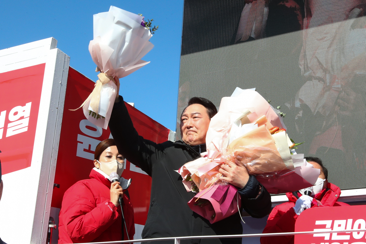 국민의힘 윤석열 대선후보가 17일 오전 경기도 용인 수지구 테이스티 애비뉴 옆 공터에서 열린 '역동적 혁신성장 대한민국 만들기' 유세에서 꽃다발을 들어 보이고 있다. [연합]