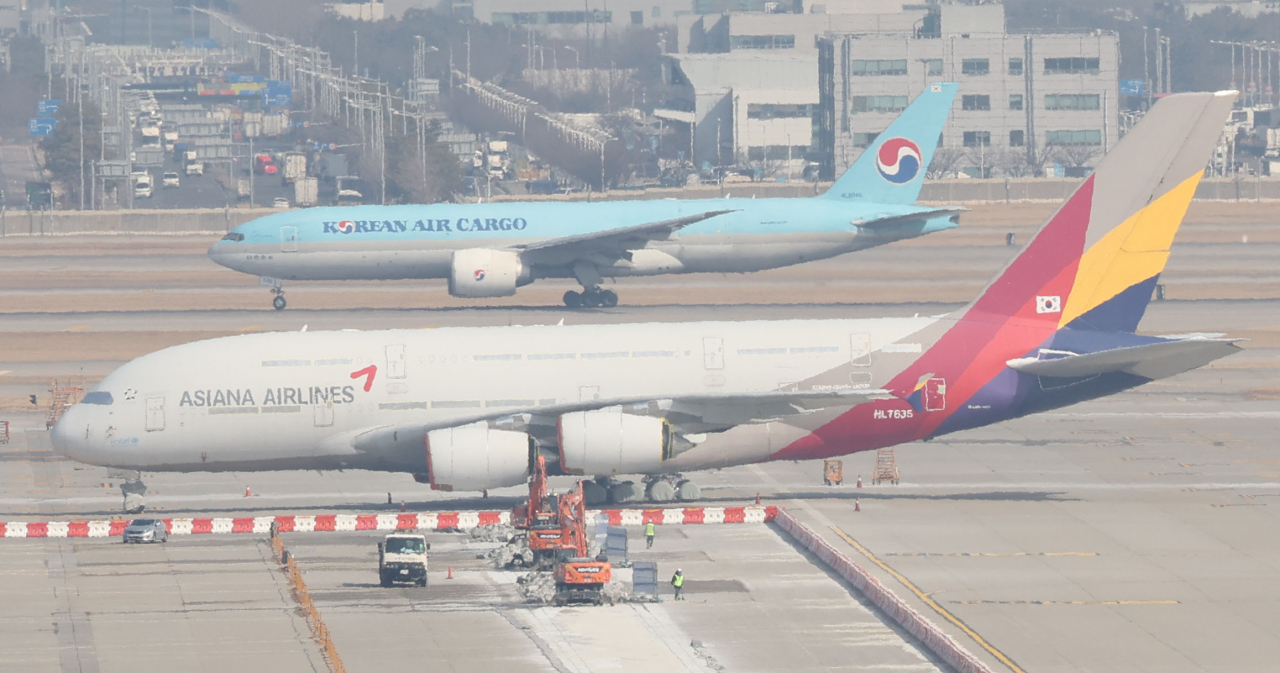 지난 9일 인천국제공항 주기장에 대한항공 항공기가 아시아나항공 건물 앞을 지나고 있다. [연합]