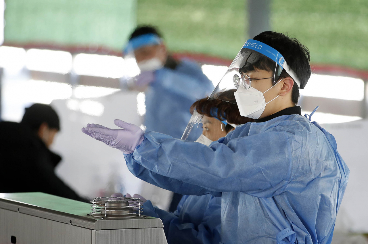 전국의 신종 코로나바이러스 감염증(코로나19) 신규 확진자 수가 10만명에 근접할 것으로 예상되는 지난 17일 광주 북구 상시 선별진료소에서 보건소 의료진이 온풍기 앞에서 몸을 녹이며 휴식을 취하고 있다. [연합]
