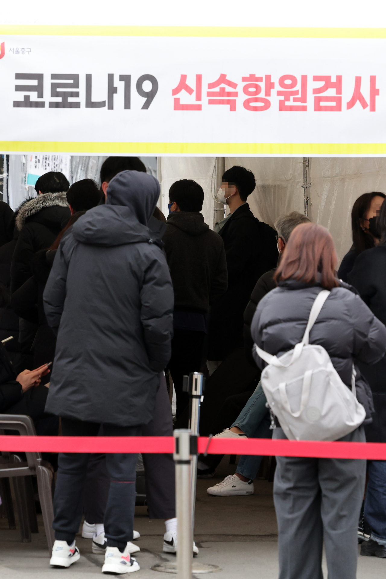 코로나19 신규확진자가 이틀째 10만 명을 넘어선 19일 오전 서울 중구 서울역 광장에 마련된 임시선별검사소의 신속항원검사 대기장소가 시민들로 북적이고 있다. [연합]