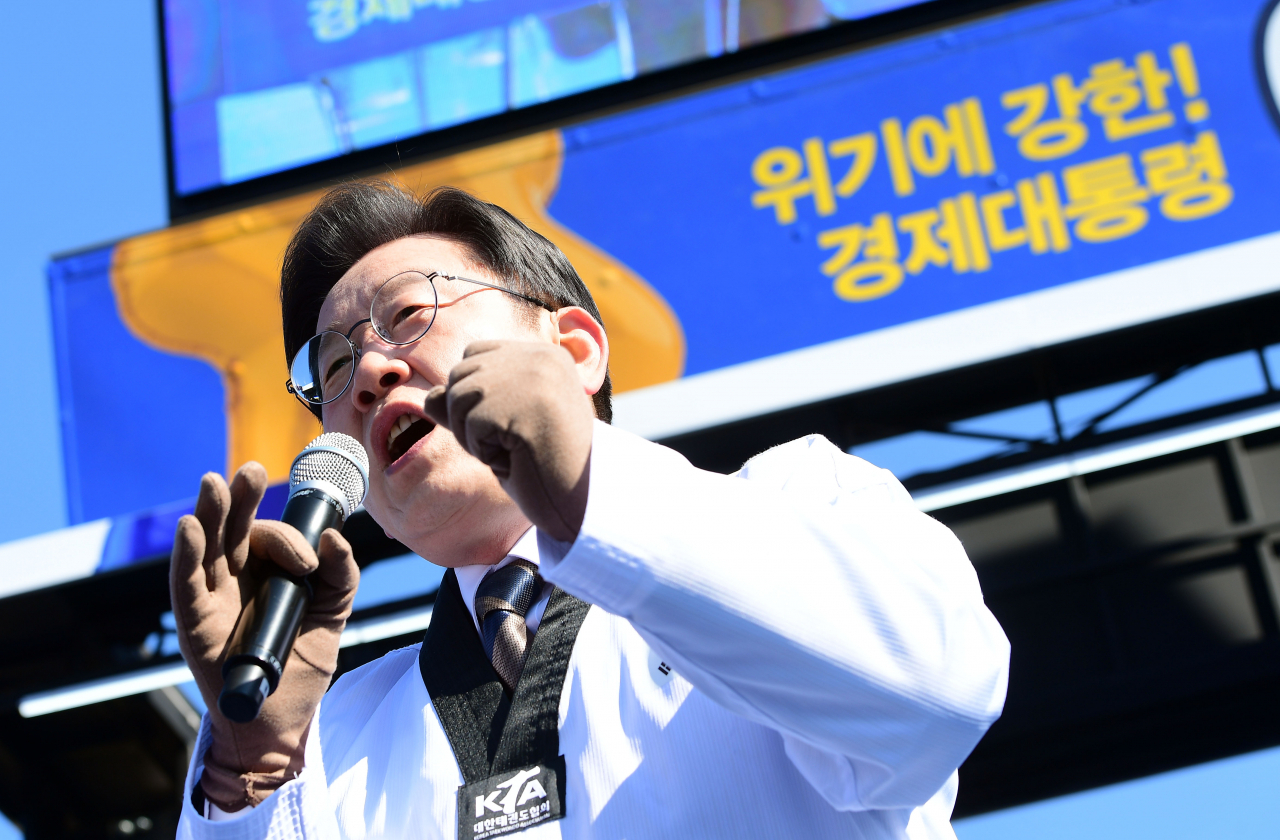 이재명 더불어민주당 대선후보가 20일 경기도 수원시 만석공원에서 열린 '검증된 실력과 성과, 대한민국을 위해 일하겠습니다!' 수원 유세에서 박상현 전 태권도 선수로부터 받은 '공약 9단' 도복을 입고 지지를 호소하고 있다. [연합]