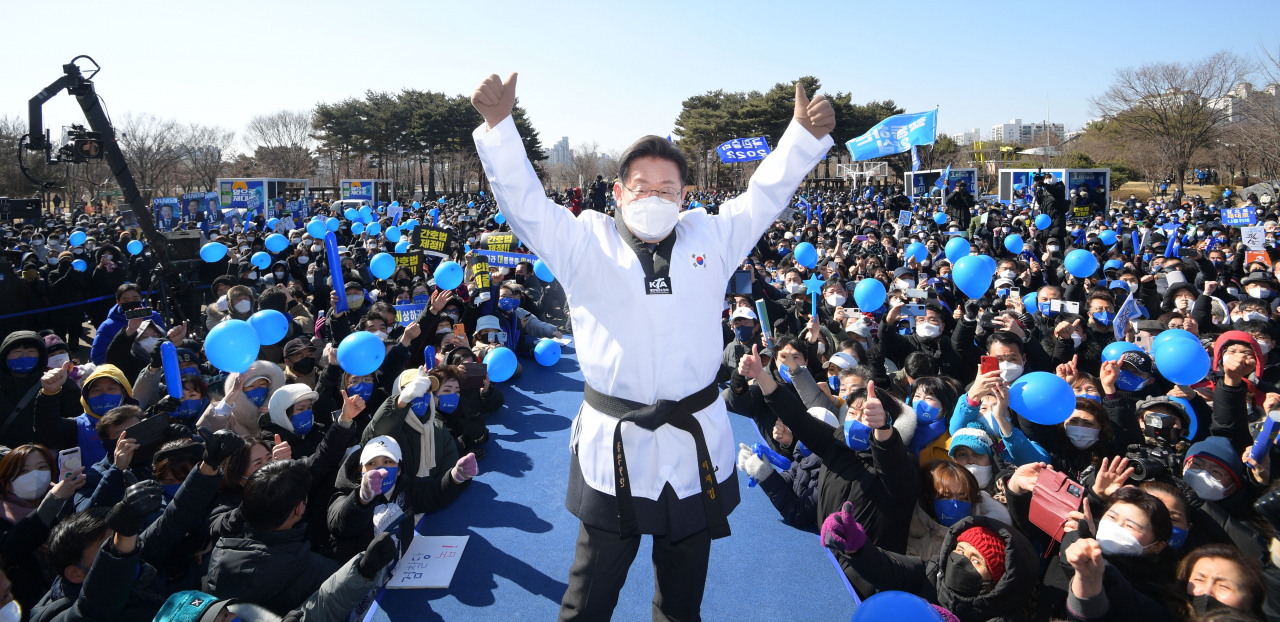 This pool photo, distributed by the National Assembly press corps, shows Lee Jae-myung, presidential candidate of the ruling Democratic Party, speaking during a campaign stop in Suwon, south of Seoul, on Sunday, while dressed in a taekwondo uniform. (National Assembly press corps)