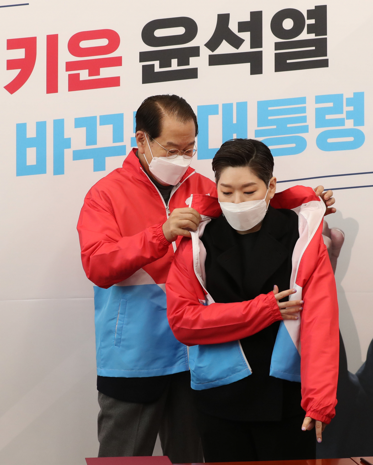 권영세 국민의힘 선거대책본부장이 21일 오전 국회에서 열린 백범 김구 선생 증손 김영 순천향대학교 의료아이티공학과 연구교수 입당식에서 김 교수에게 당 점퍼를 입혀주고 있다. [연합]