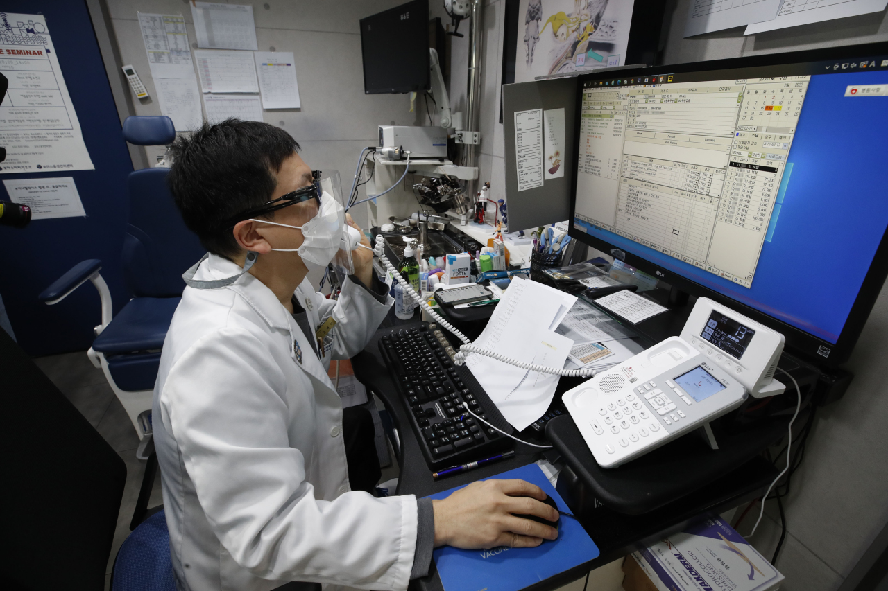 A primary physician speaks with home-isolating patients over the phone. From Feb. 10 the remote monitoring is offered only to patients 60 and older. (Yonhap)