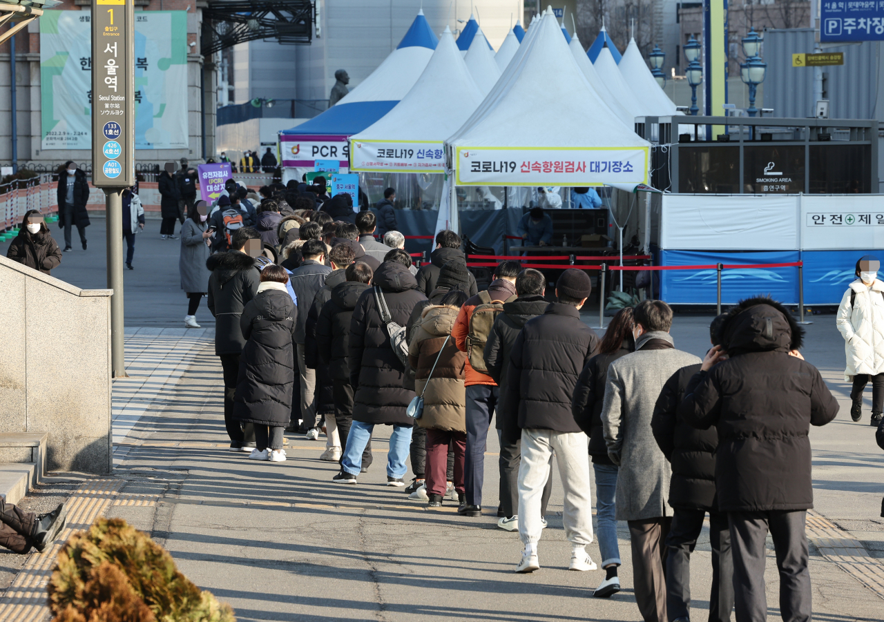 People wait in line to receive COVID-19 tests at a makeshift testing station in Seoul on Tuesday. (Yonhap)
