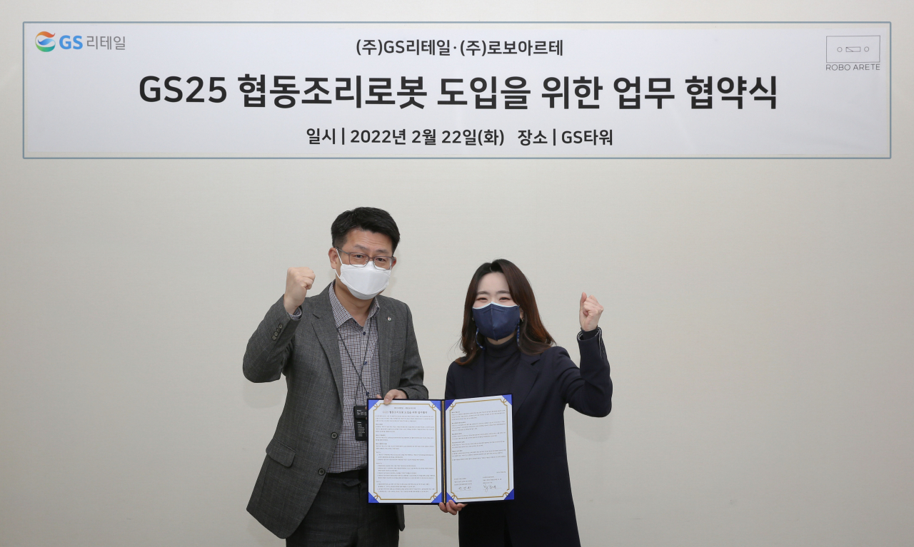 이달 22일 GS타워 지하1층 식품개발팀 회의실에서 권영환 GS리테일 간편식품부문장(왼쪽)과 강지영 로보아르테 대표이사(오른쪽)가 업무협약을 맺고 기념촬영을 하고 있다. [GS리테일 제공]