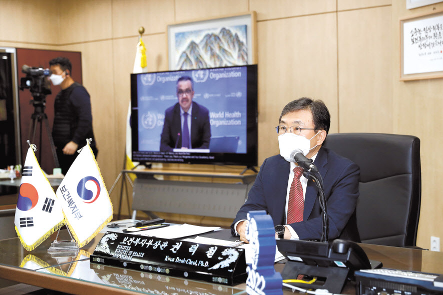 권덕철 보건복지부 장관이 23일 화상으로 열린 글로벌 바이오 인력양성 허브 지정 발표 관련 브리핑서 테드로스 아드하놈 게브레예수스 WHO 사무총장과 대화하고 있다. [보건복지부 제공]