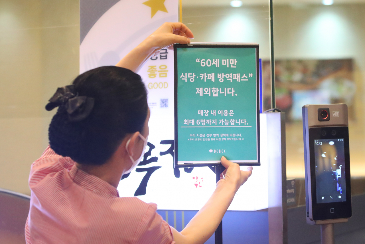 24일 오전 대구 중구 대구백화점 프라자점 내 식당 직원이 방역패스 안내문을 교체하고 있다. 전날 대구지법은 청소년 방역패스에 이어 60세 미만에 대한 식당·카페 방역패스 효력정지 결정을 내렸다. [연합]