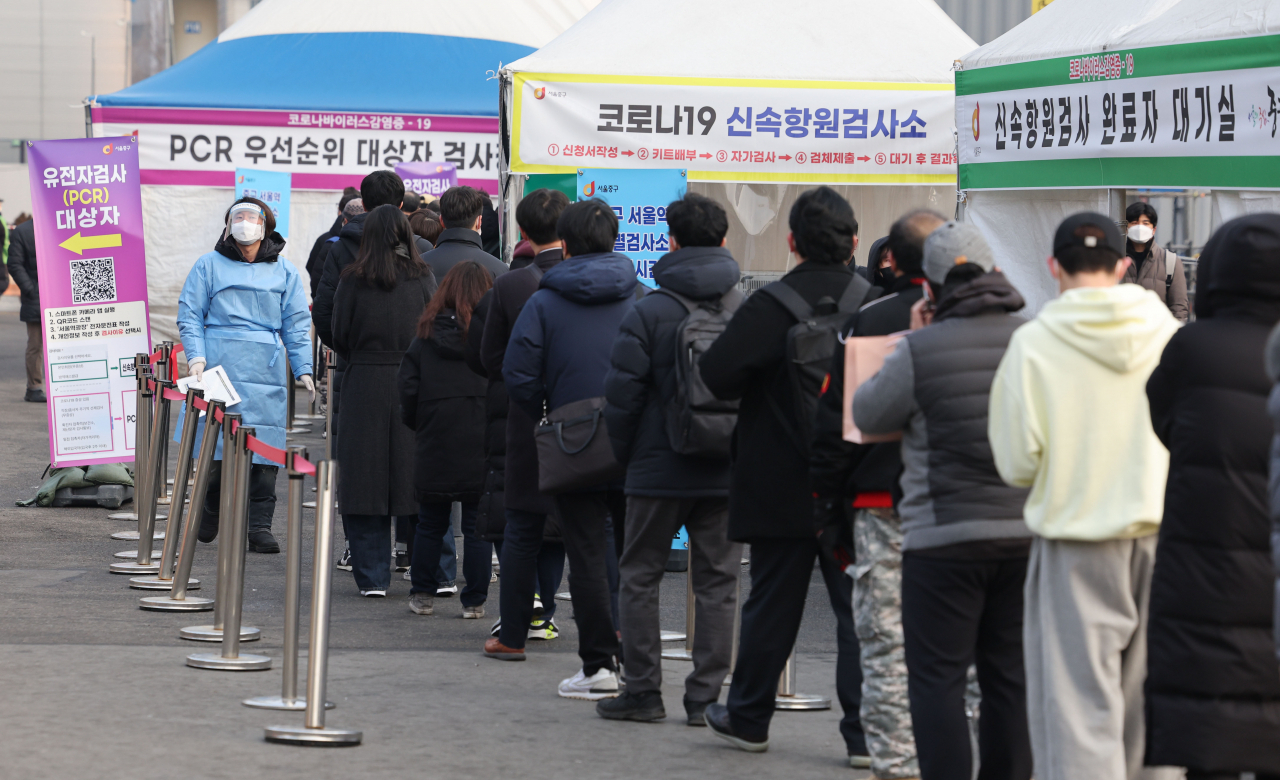People wait in line to receive COVID-19 tests at a makeshift testing station in Seoul on Friday. (Yonhap)