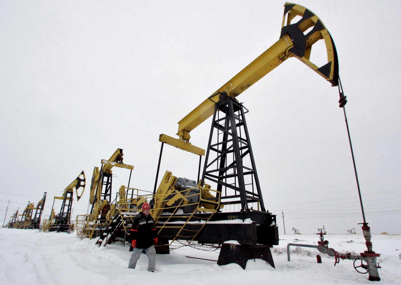 FILE PHOTO: A worker walks past pump jacks at UdmurtNeft's Gremikhinskoye oil field east of Izhevsk near the Ural Mountains December 7, 2007. REUTERS/Sergei Karpukhin (RUSSIA)/File Photo