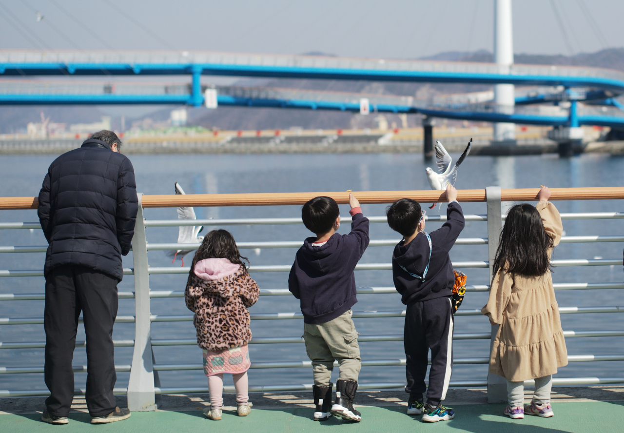 지난 25일 오후 경남 창원시 마산합포구 서항지구 친수공간에서 아이들이 갈매기에게 먹이를 주고 있다. [연합]