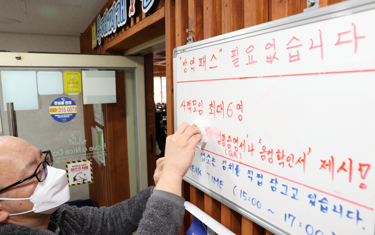 28일 오후 서울 종로구 한 식당에서 관계자가 기존 방역패스 안내문을 수정하고 있다. 이날 이 음식점은 내부사정으로 단축 영업을 한 뒤 방역패스 중단 관련 준비를 했다. [연합]